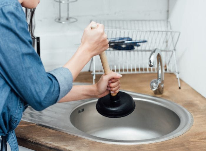 partial-view-of-woman-in-denim-shirt-using-plunger-2023-11-27-05-04-34-utc-qovajj93h7t3i5z0zrc0wu8kmk2goyu5dydl8qjxni-min Clogged Drain Clearing Photo